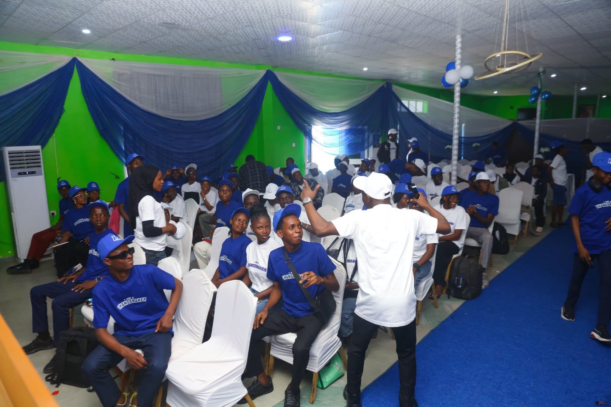 Members in blue and white Changemaker T-shirts and caps cheering during a session